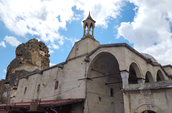 Ortahisar Abdioğlu Camii ve arka planda Ortahisar Kalesi; taş mimarisi ve kemerli yapısıyla Kapadokya kasaba dokusu